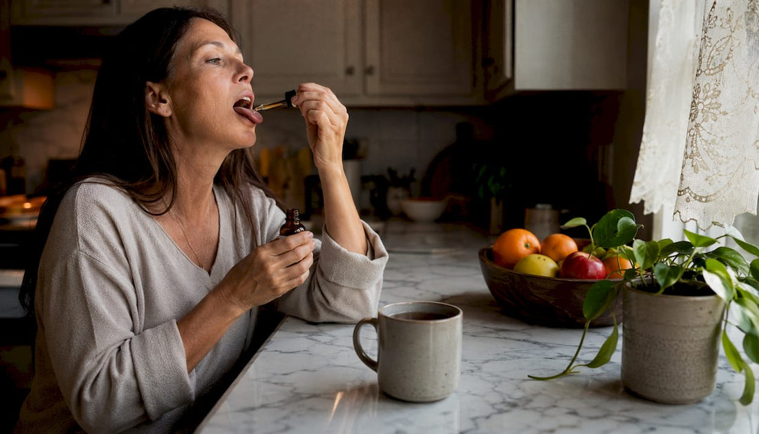 Woman taking CBD tincture sublingually at kitchen table
