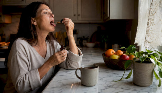 Woman taking CBD tincture sublingually at kitchen table