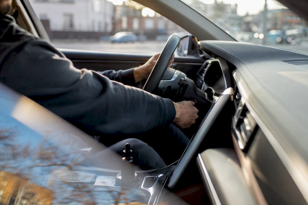 Driver's hand on car key with CBD bottle blurred