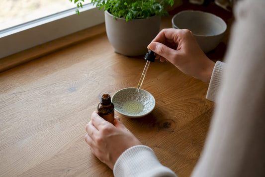 Hand pouring CBD oil with hemp plant nearby